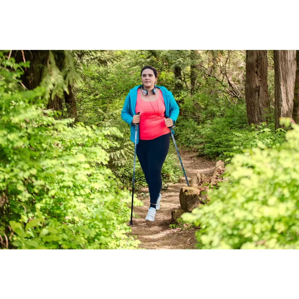 Woman with walking poles on a path in a forest
