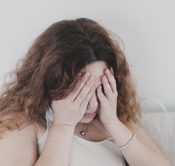 Woman Holding Hands Against Face as if in Pain