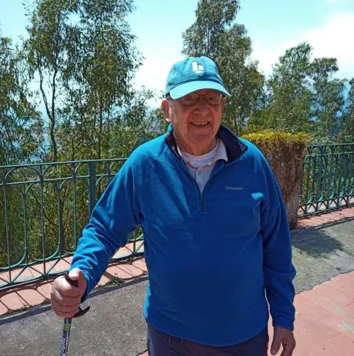 Man with walking poles with trees, sky and railing in background