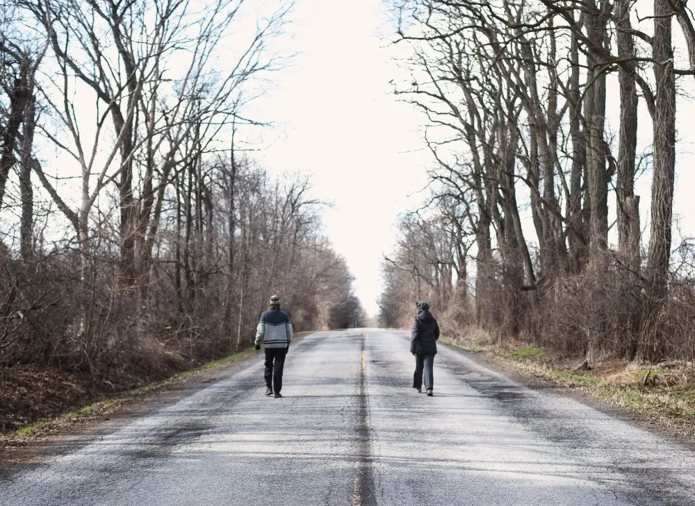 Two People Walking on an Empty Road