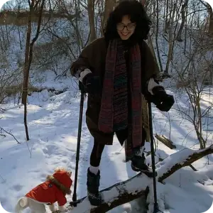 Woman with forearm crutches balancing on a log in the winter