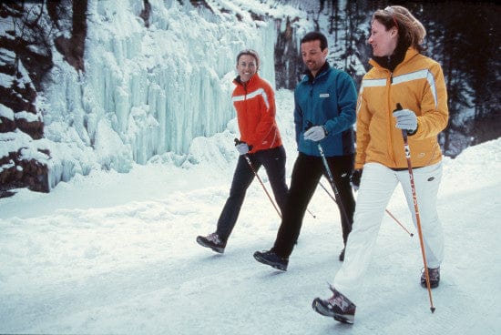 Three people pole walking on a snowy path