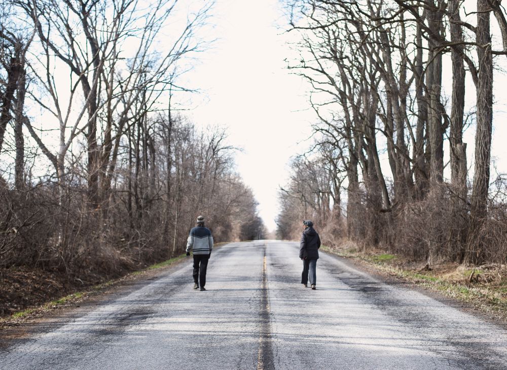 Two People Walking on an Empty Road
